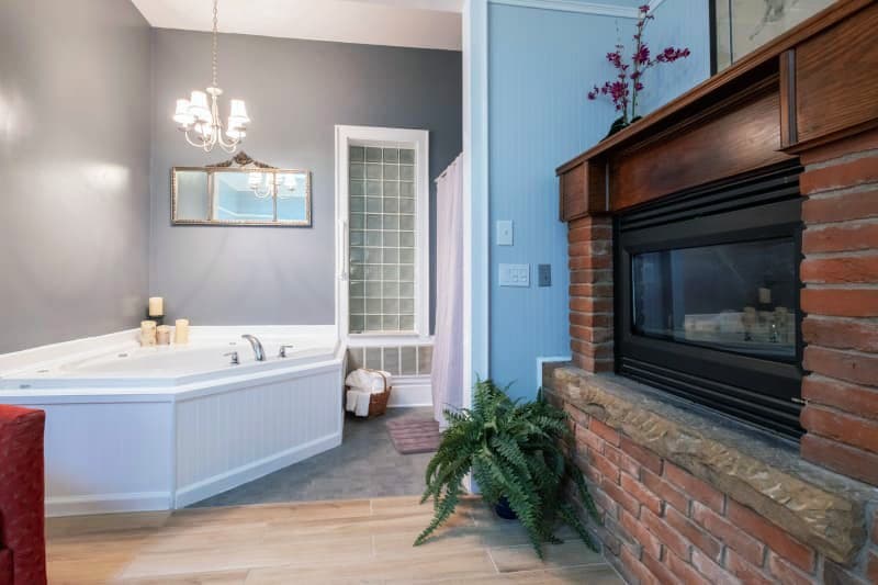 A stylish bathroom featuring a jacuzzi, fireplace, and chandelier.