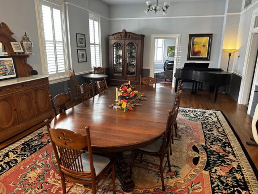 A spacious dining room featuring a large wooden table, elegant chairs, and a decorative floral centerpiece.